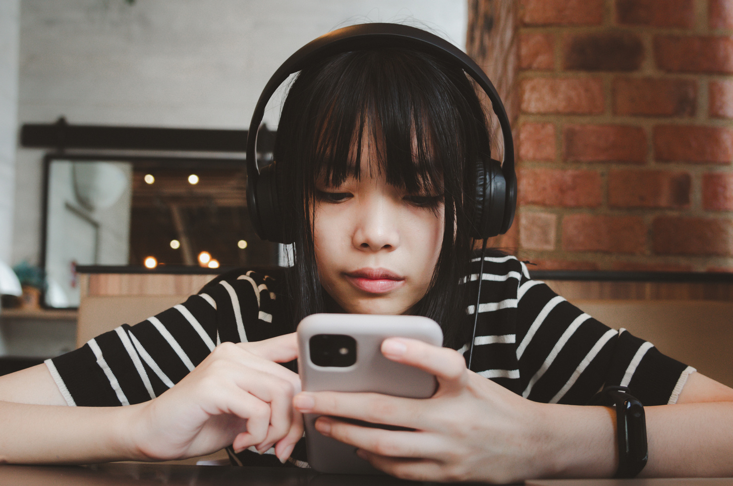 Teenage girl wearing headphones and holding a cell phone sma